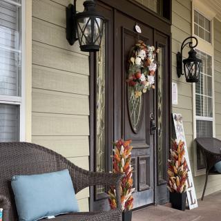A cozy front porch with fall decorations and comfortable seating.