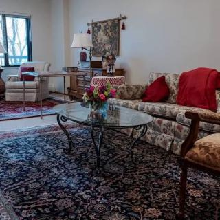 A cozy living room with patterned sofas, a glass coffee table, and decorative rugs.