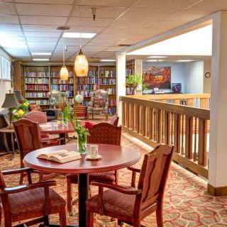 A cozy library space with tables, chairs, and bookshelves, offering a warm and inviting atmosphere.