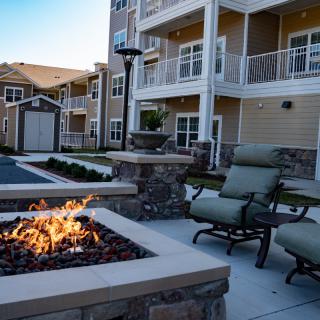 A cozy outdoor seating area with a fire pit at an apartment complex.