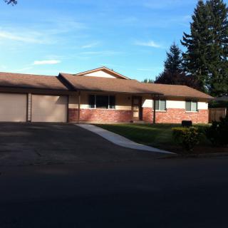 A suburban brick house with a driveway and a front lawn.