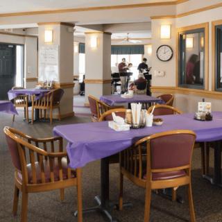 An empty restaurant dining area with tables covered in purple tablecloths.