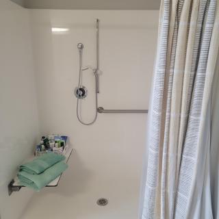 A clean and minimalistic shower setup with a curtain and towels neatly placed on a shelf.