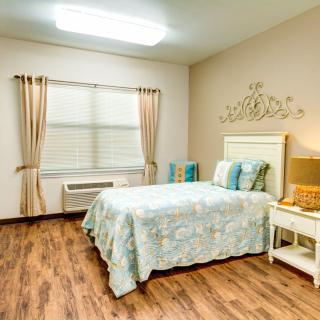 A cozy bedroom with a neatly made bed, decorative elements, and a wooden floor.