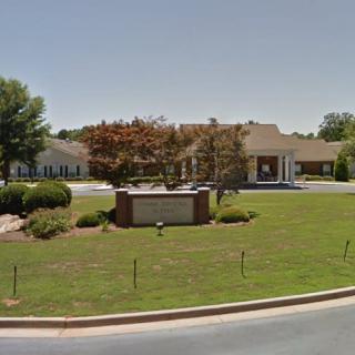 A view of a building with a sign and a well-maintained lawn under a clear sky.