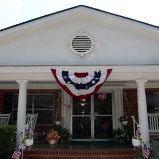 A charming house adorned with patriotic red, white, and blue bunting on the front porch.