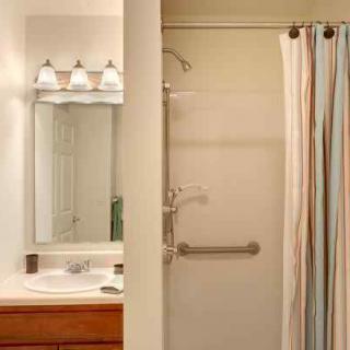 A bathroom featuring a sink with a mirror, a shower with a curtain, and overhead lighting.