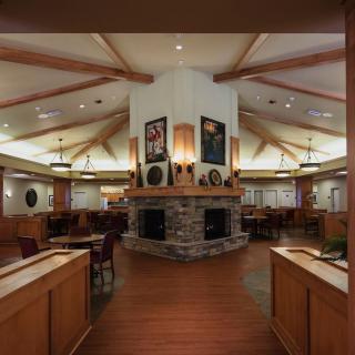 A cozy restaurant interior featuring wooden furniture and a central fireplace.