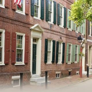 Historic brick row houses with black shutters and an American flag on a quiet street.