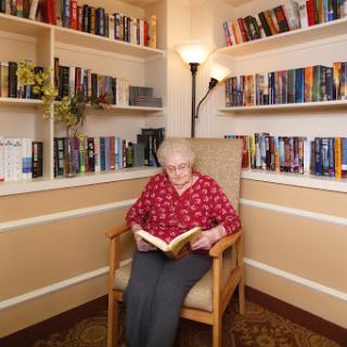An elderly person enjoying a quiet moment with a book in a cozy reading nook.