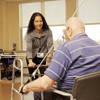 A physical therapist assists an elderly man during a rehabilitation session.