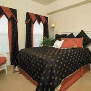 A well-decorated bedroom with matching black and red bedding and curtains.