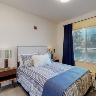 A cozy bedroom with a neatly made bed and large window.