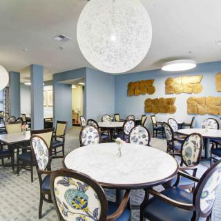 A modern dining room with round tables, elegant chairs, and stylish lighting fixtures.