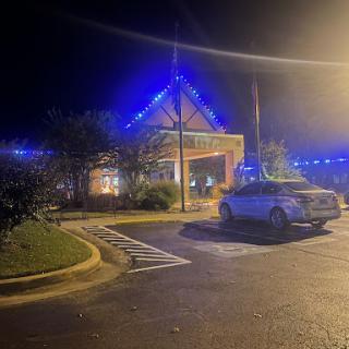 A well-lit building at night adorned with blue lights, surrounded by a parking lot.