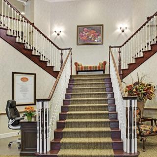 A well-lit lobby featuring a grand staircase with elegant decor.