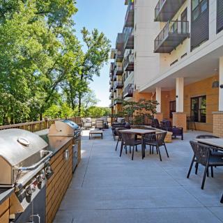 A spacious outdoor patio with grills and seating next to an apartment building.