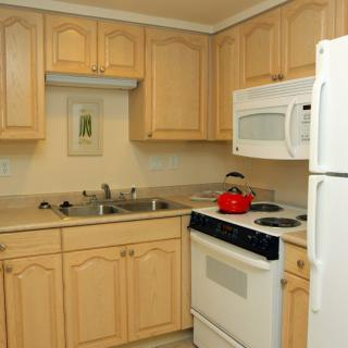 A cozy kitchen with wooden cabinets, a stove, microwave, refrigerator, and a double sink.