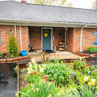 A cozy brick house with a vibrant garden in the front yard.