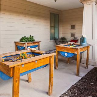 A cozy outdoor children's play area featuring wooden sand tables and educational toys.