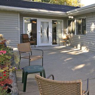 A peaceful backyard patio area with chairs, leading to the house through French doors.