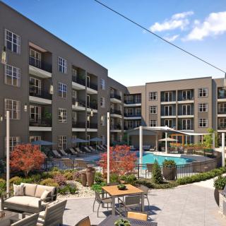 A modern apartment complex featuring a well-manicured courtyard with a swimming pool and outdoor seating area.