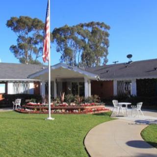 A well-maintained building surrounded by a garden with an American flag in front.