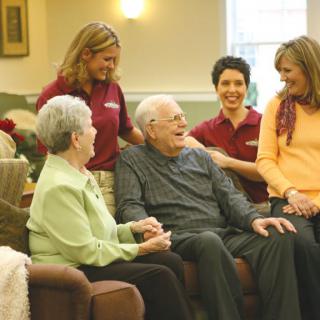 Healthcare workers interacting with seniors in an assisted living facility.