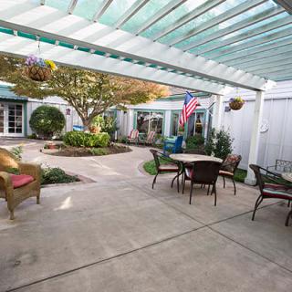 A tranquil courtyard with a pergola, outdoor seating, and lush garden landscaping.