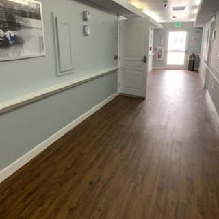 A long hallway with wooden flooring and picture frames on the wall.