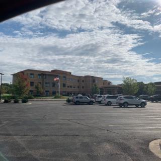 A view of a modern building adjacent to a spacious parking lot under a partly cloudy sky.
