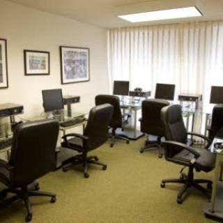 An empty office conference room with chairs and desks equipped with computers.