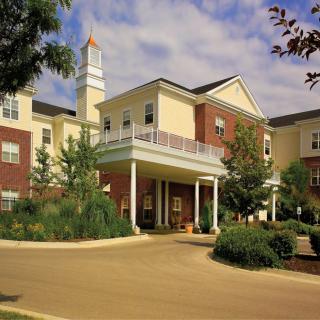 A modern residential building with landscaped gardens under a clear sky.