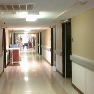 A quiet hospital corridor with closed doors and a nurse's station.