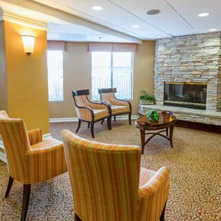 A modern living room with striped chairs and a stone fireplace.