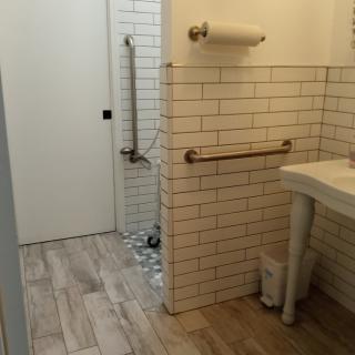A modern bathroom with tiled walls, a sink, and wooden flooring.