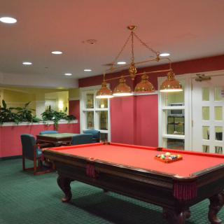 A stylish billiard room featuring a red pool table under a classic hanging light fixture.