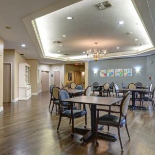 A well-lit dining area with several tables and chairs arranged on polished wooden flooring.