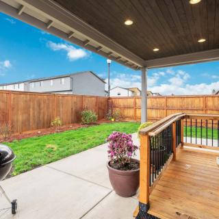 A serene backyard with a covered patio, wooden deck, and green lawn.