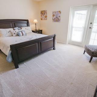 A well-lit bedroom with a large bed, carpeted floor, and stylish decor.