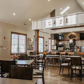 A modern caf� interior featuring a cozy dining area with wooden furniture and bright lighting.