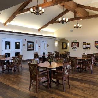 A spacious dining area with wooden tables, chairs, and decorative chandeliers.