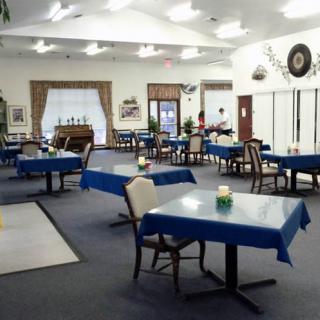 An empty dining room with tables covered in blue tablecloths.