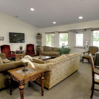 A cozy living room with multiple seating options, a television, and large windows.