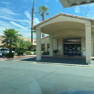 A welcoming entrance to a commercial building, framed by palm trees under a bright blue sky.