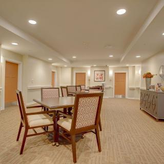A cozy dining area with a table and chairs, surrounded by soft lighting and carpeted flooring.