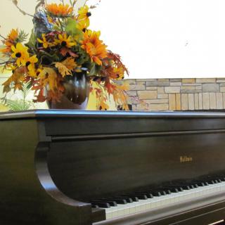 A grand piano adorned with a vibrant autumn floral arrangement.