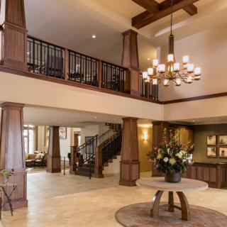 A spacious lobby area with a grand chandelier, wooden beams, and elegant decor.