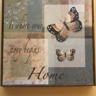 Decorative artwork featuring butterflies and an inspirational quote about home.