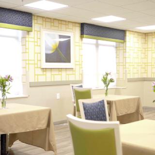 A well-lit dining area featuring elegant tables and chairs, complemented by floral arrangements and wall art.
